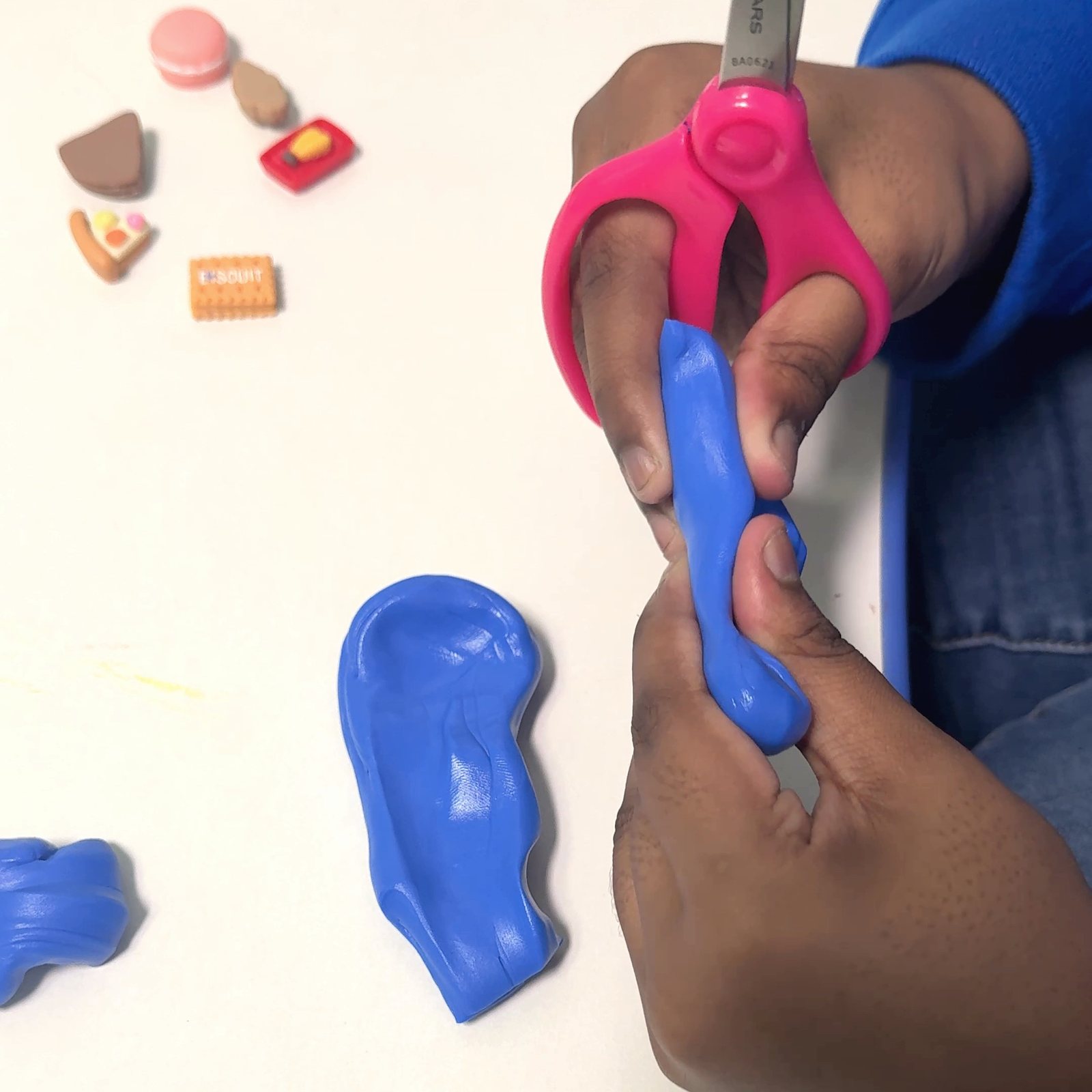 A child's hands cut playdough with child-safe scissors