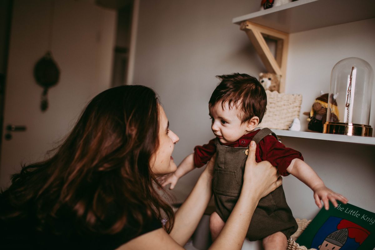 A mother and her young son play and talk together on the living room floor